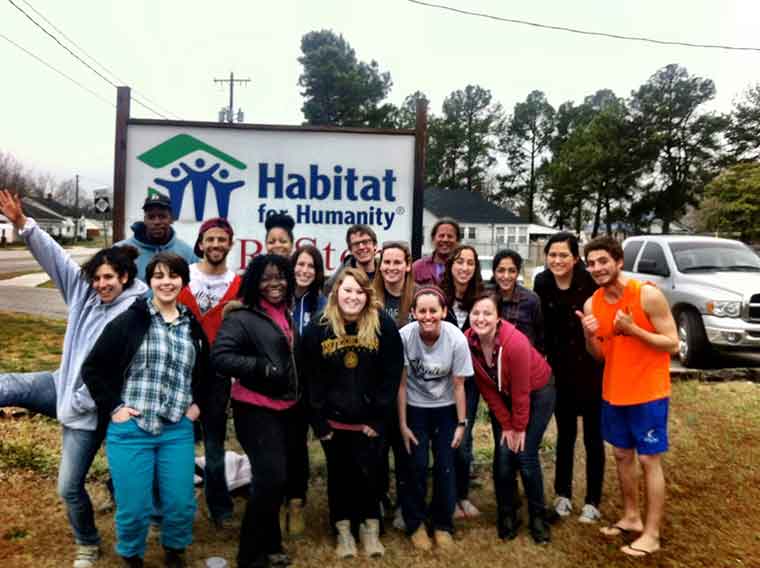Student volunteers in front of a Habitat for Humanity sign