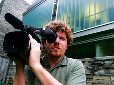 A man pointing a camera outside the Heimbold Visual Arts Center