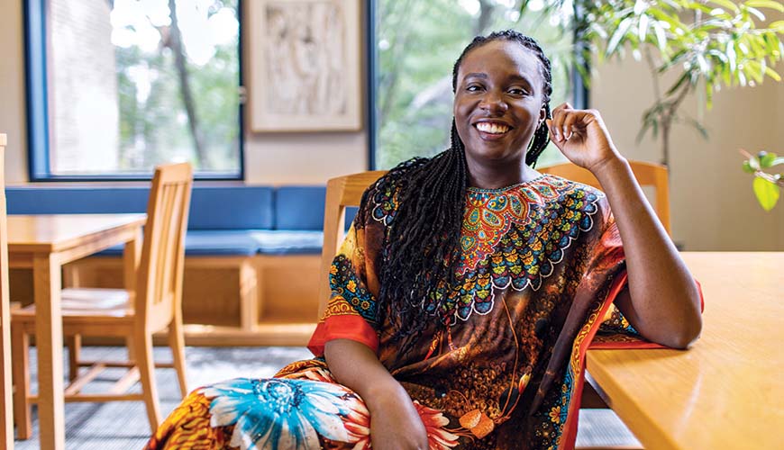 student with long braids and colorful clothing seated at table