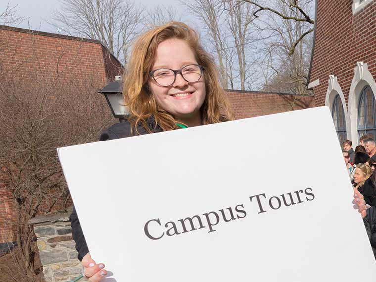 Woman holdig a sign that says Campus Tours