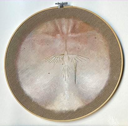 Embroidery hoop with a bird design on a textured, circular fabric background.