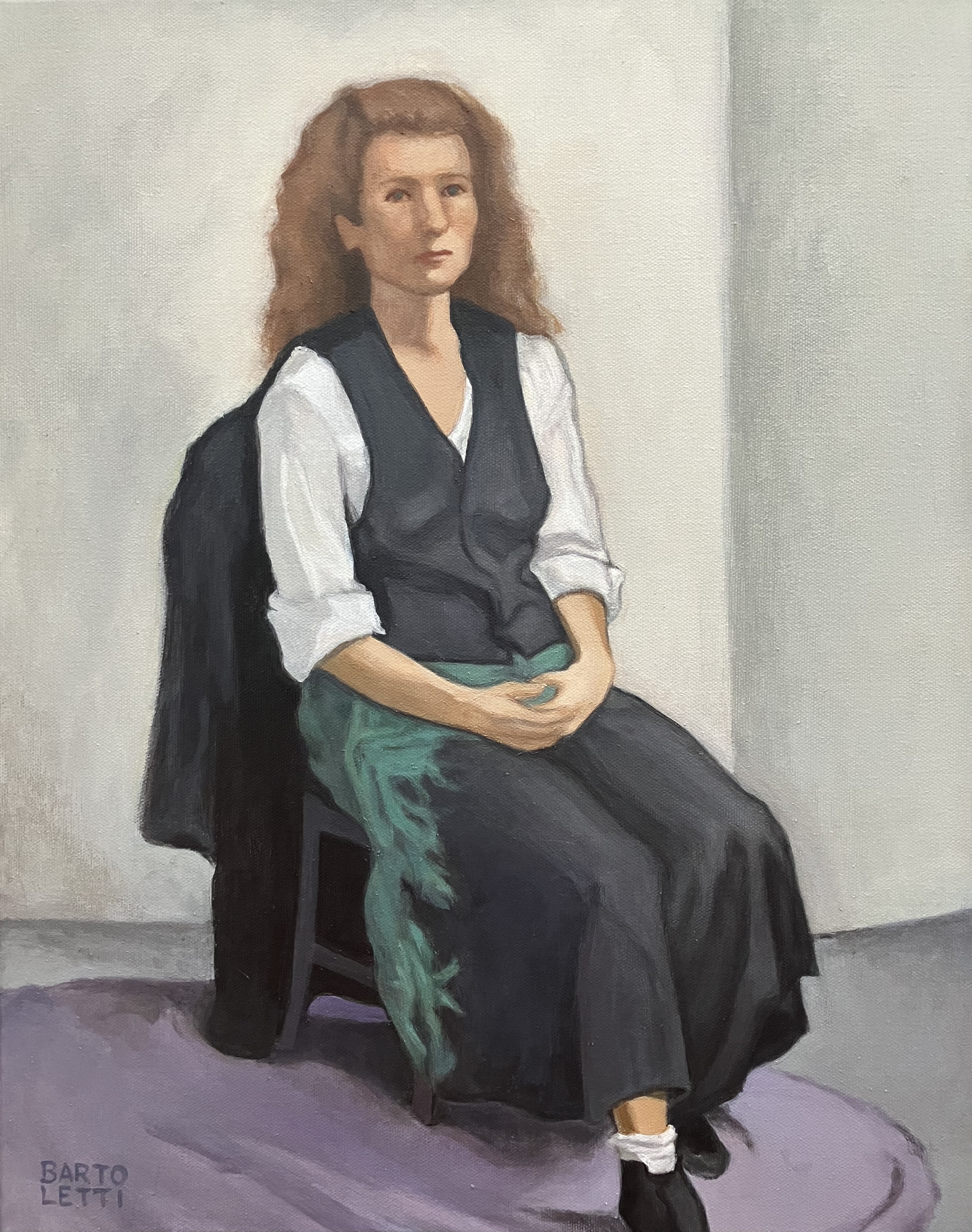Person with long hair seated on a chair, wearing a white shirt, dark vest, long skirt, and black shoes, holding hands together.