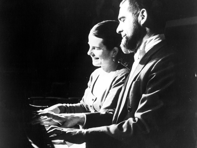 Black and white photo of two people playing piano