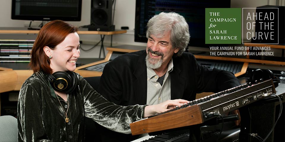 Student with headphones sitting with faculty member at mixing board in music studio