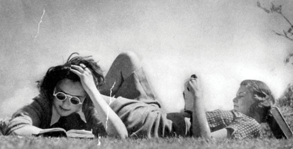 Archival image of students studying outside on the grass