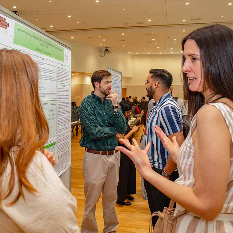 student and faculty in discussion in front of science poster