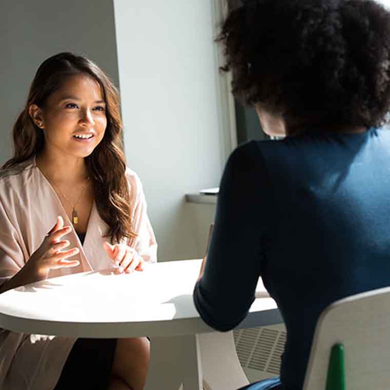 two people seated at a table in coversation