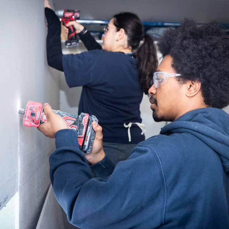 student volunteers cutting sheetrock