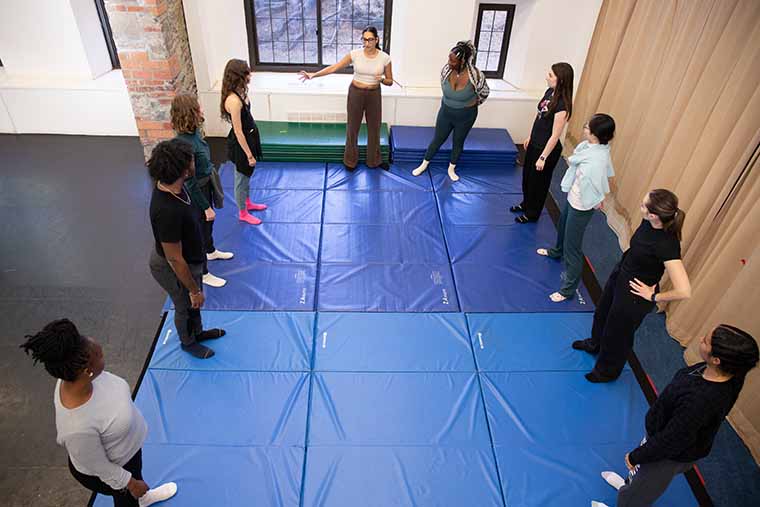 Overhead view of students standing around perimeter of exercise mats