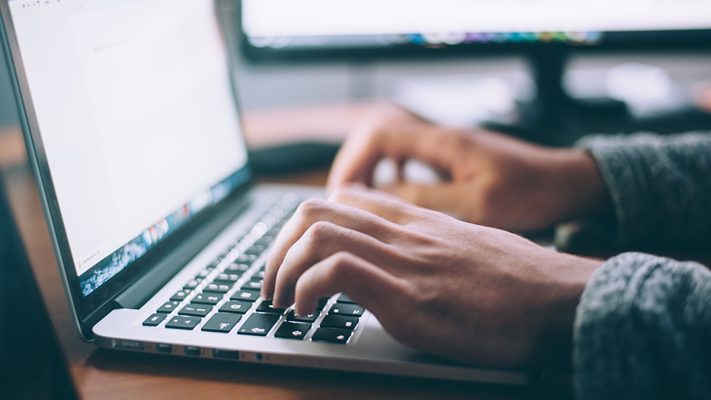 Hands typing on a laptop