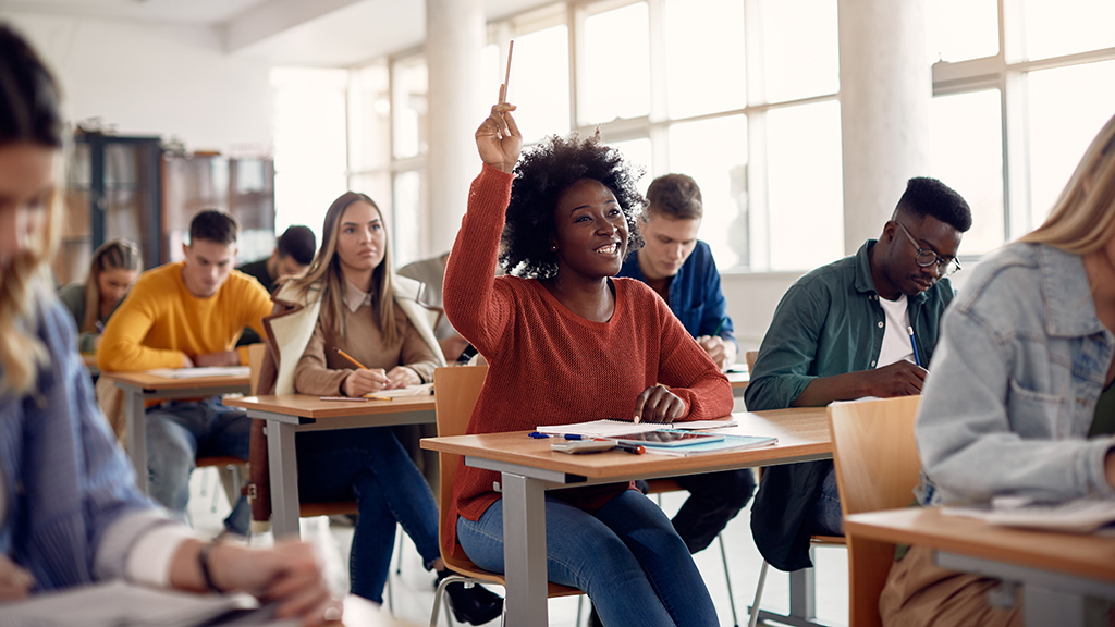 A smiling student raising her hand in class