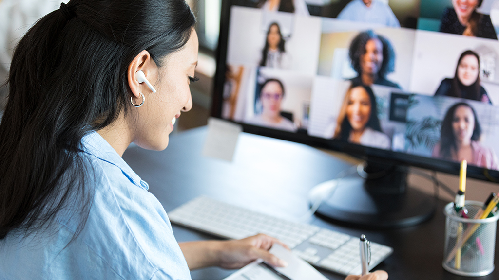 A woman taking notes while in a Zoom meeting