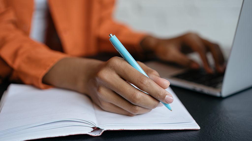 A hand writing in a notebook