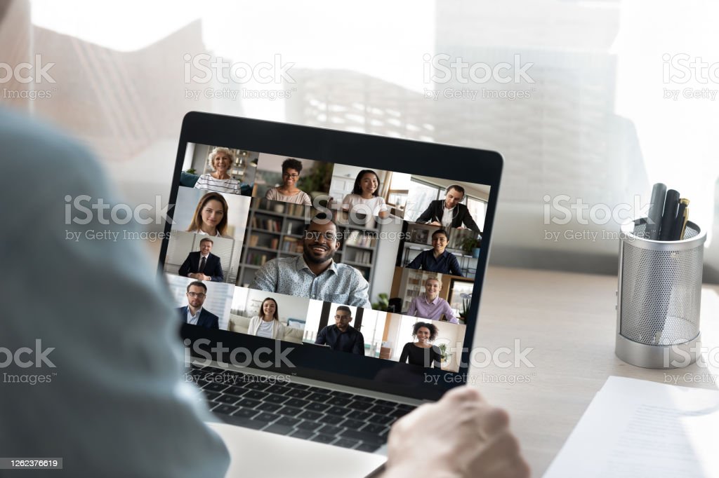 Hands holding a laptop with a Zoom meeting on the screen
