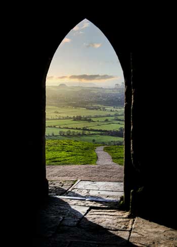Doorway looking out onto green grass field with path through it in daytime