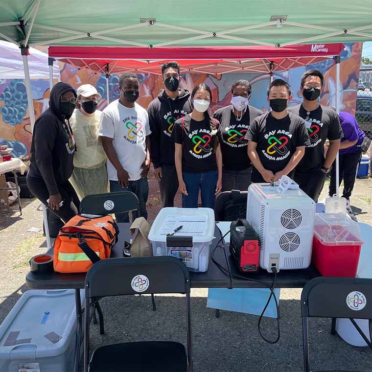 Group of volunteers gathered behind table with vaccination equipment