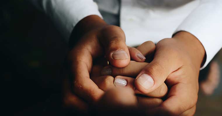 pair of hands wrapped around a smaller pair of hands