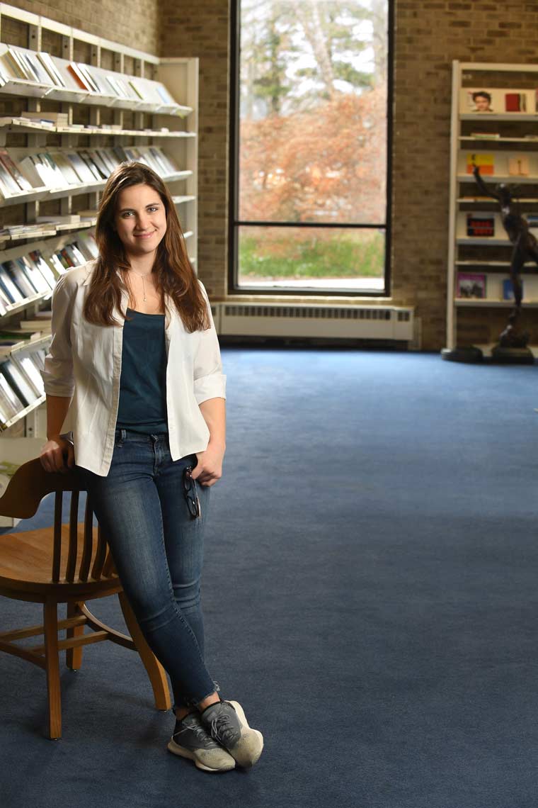 Woman leaning on chair near bookshelves