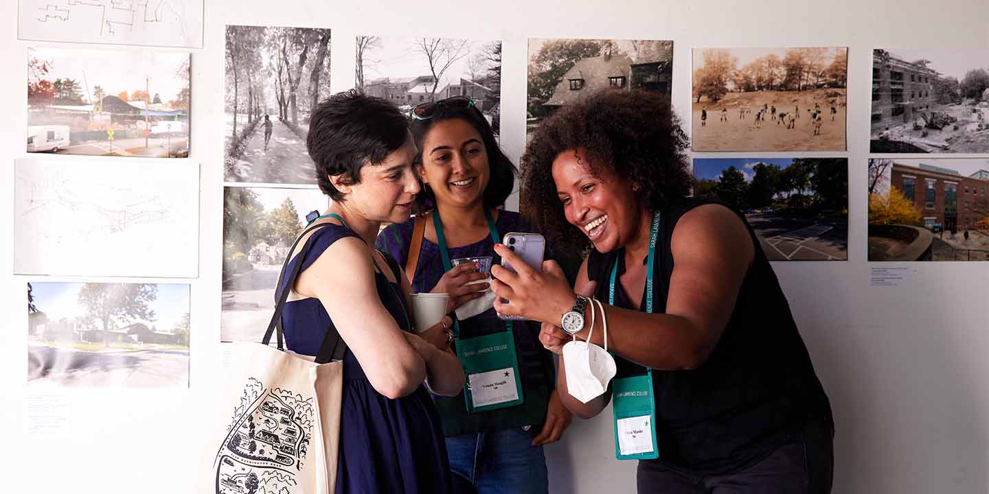 Three alums standing in front of artwork on the wall