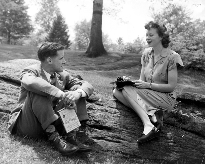archival photo of male and female student seated outdoors