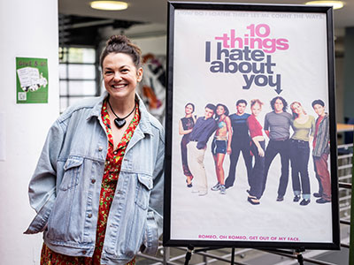 Larisa Oleynik posing next to a 10 Things I Hate About You movie poster