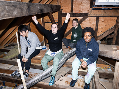 Students taking a break in the attic of a home they're helping to refurbish