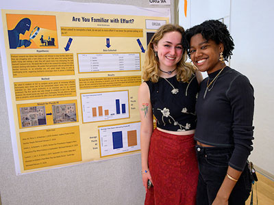 Two students smile in front of a poster at the science poster session