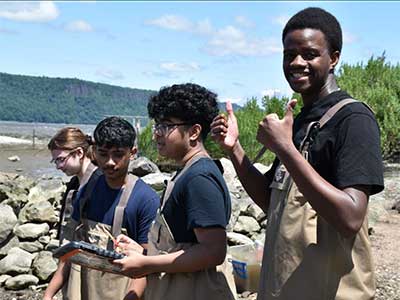 Students smile by the river while doing research