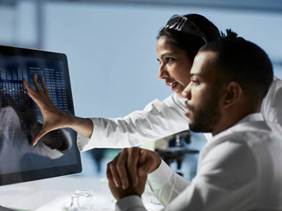 Two people analyzing data on a computer screen