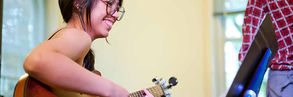 Student smiling, playing jazz guitar