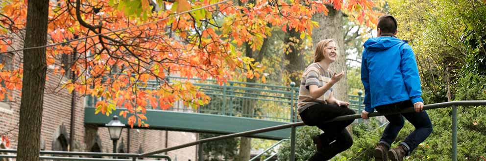 Students talking while sitting on railing