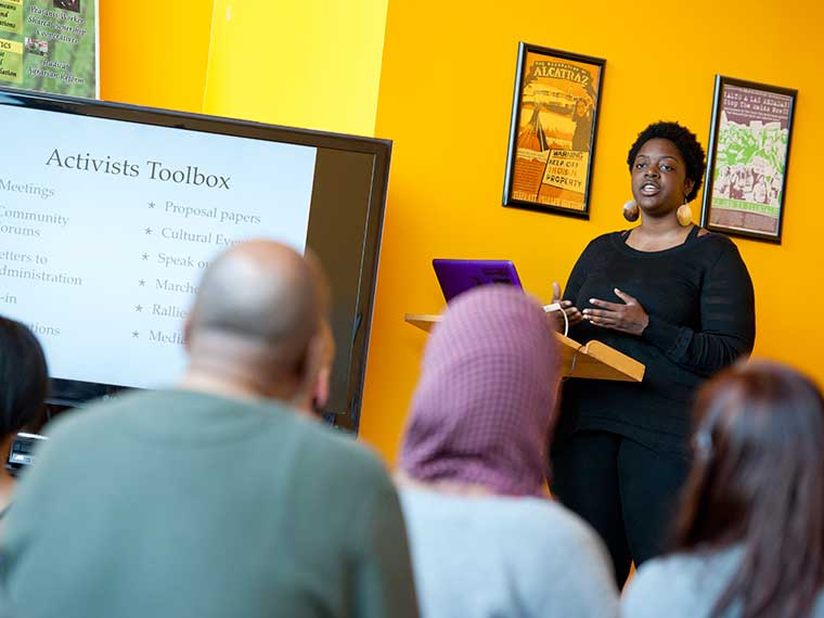 An audience listening to a woman giving a lecture