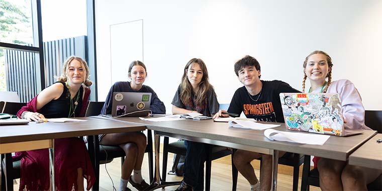 group of student seated in classroom at large table facing camera