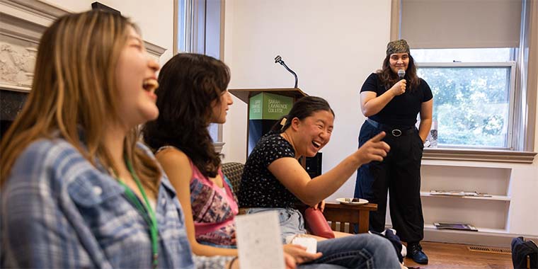 group of students laughing and gesturing to each other seated on a couch