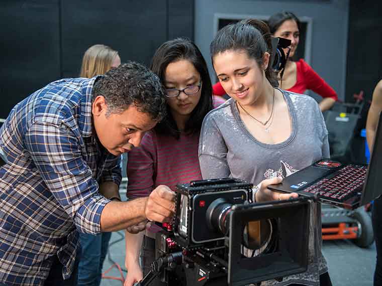 Faculty member looking through video camera with student