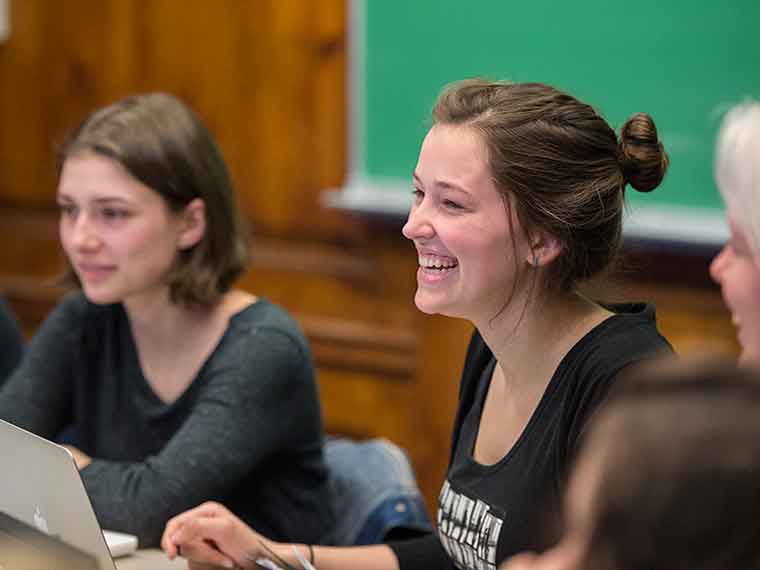 Student smiling in classroom with another student in background
