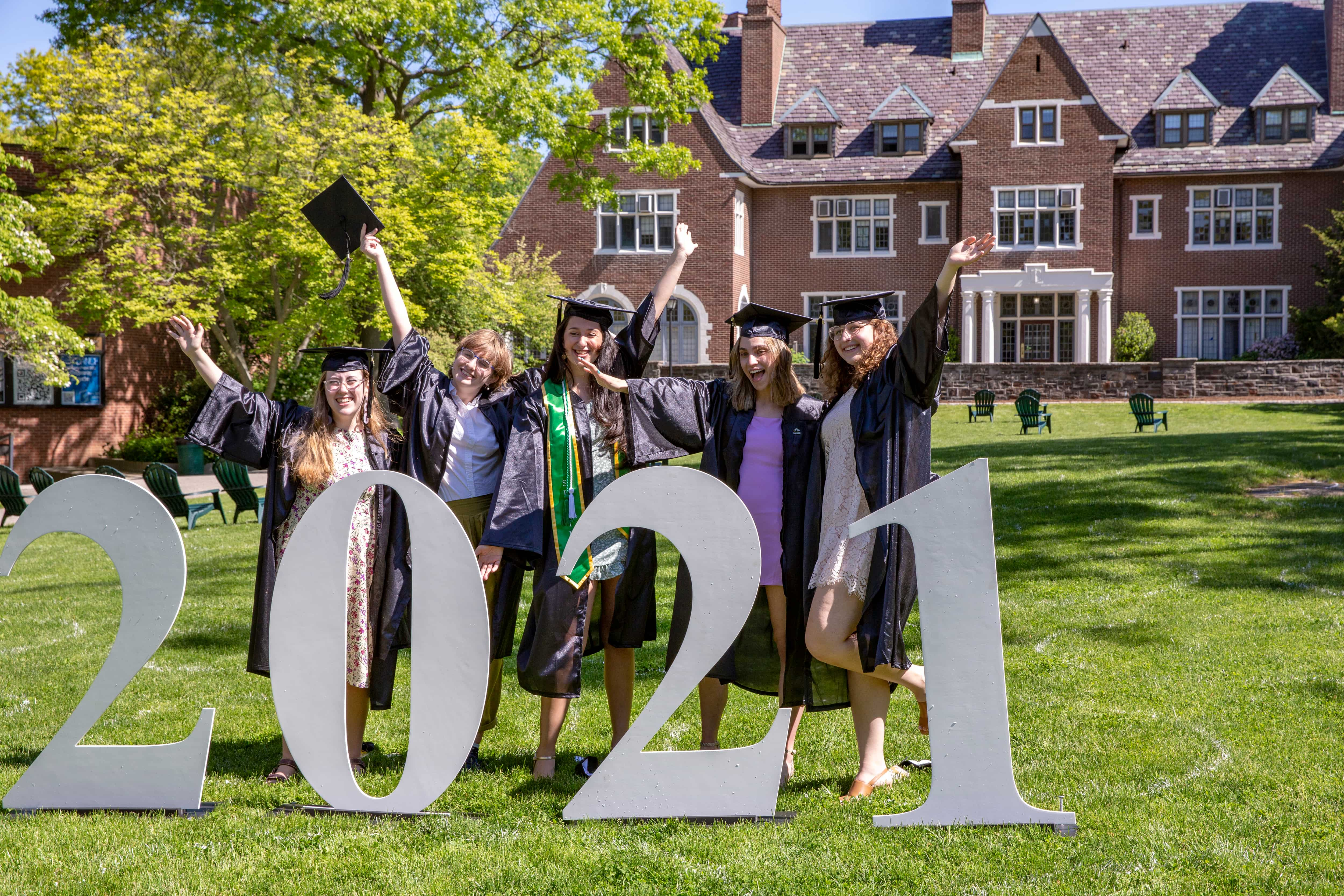 Graduates standing with large 2021 number cutouts