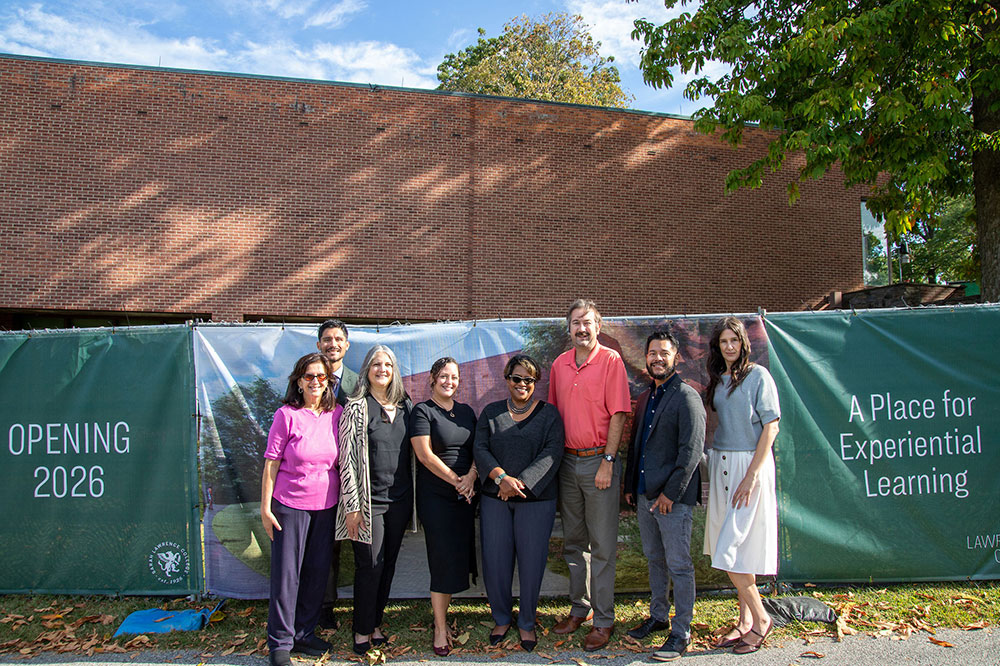 Group of staff members smiling outside construction fence