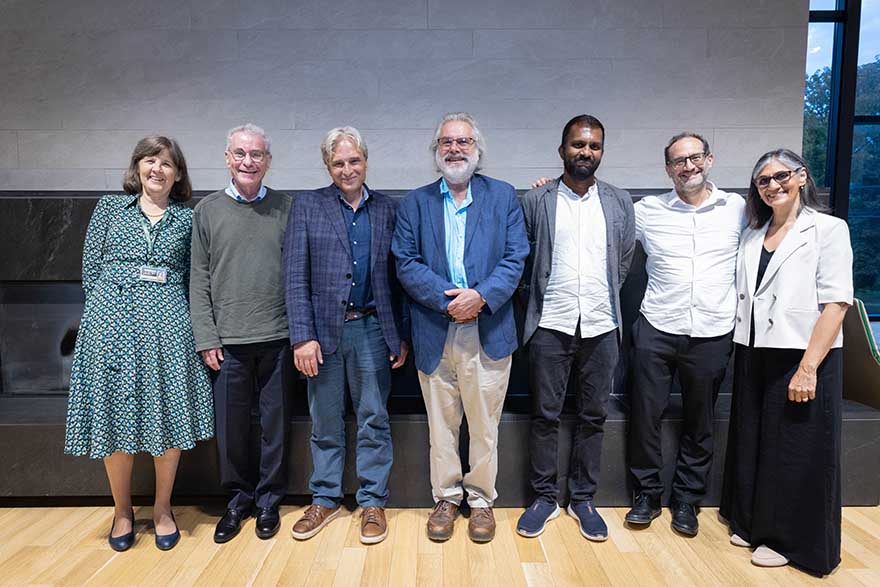 Two women and four men standing and smiling at camera