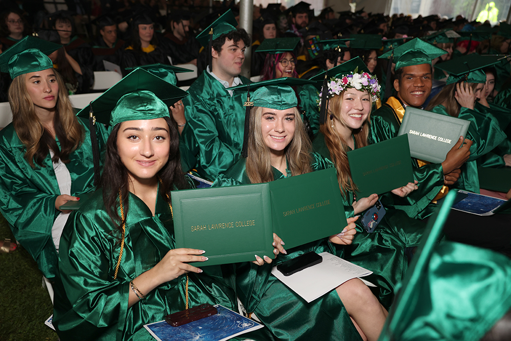 Graduates smiling and holding up their diplomas