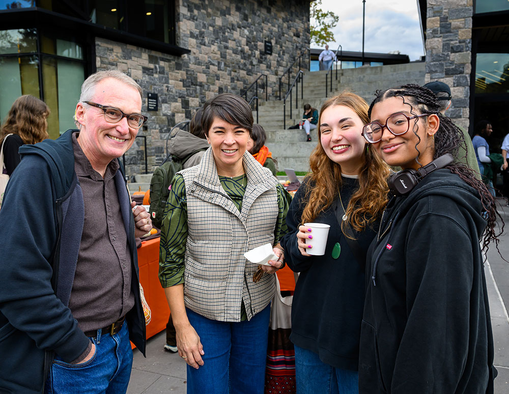 Family smiling in front of campus center
