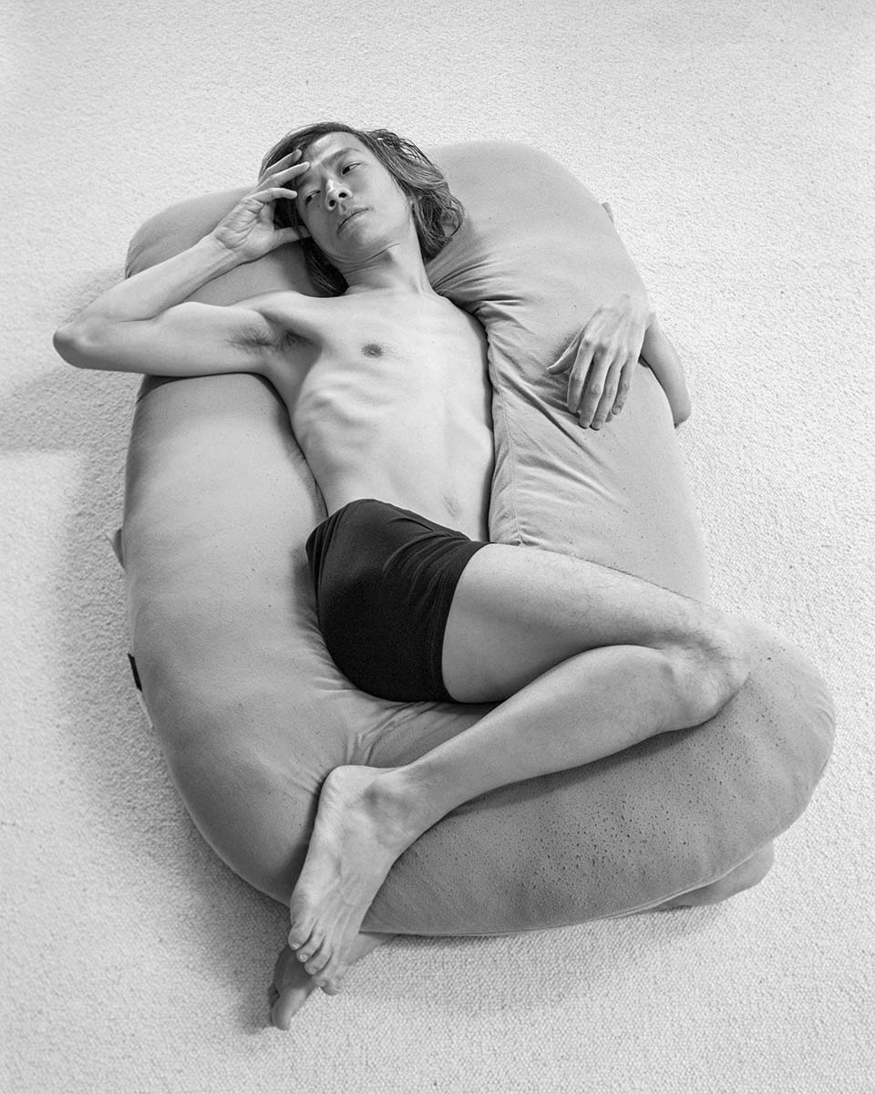 black and white photograph of man wrapped around pillow