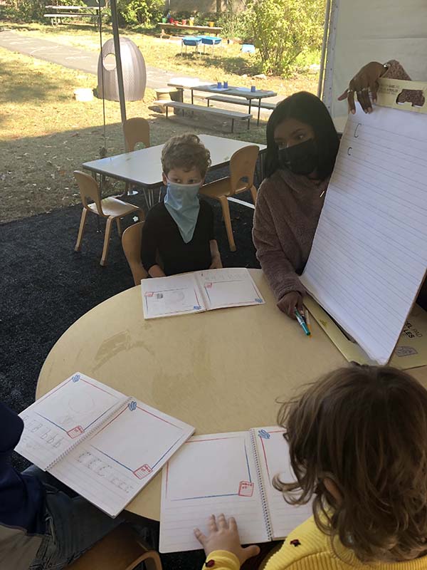 Teacher and students studying under a tent