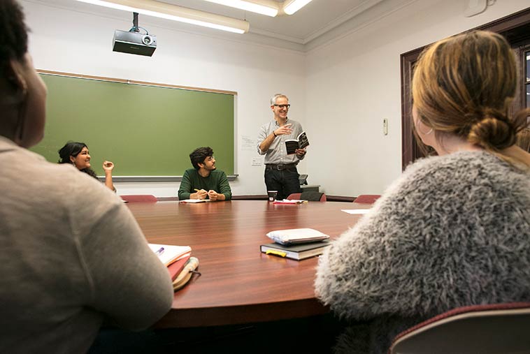 Students around conference table listening to faculty member.