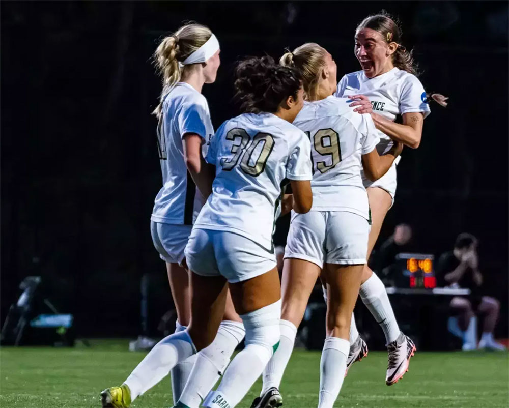 Women's soccer players celebrating on a field