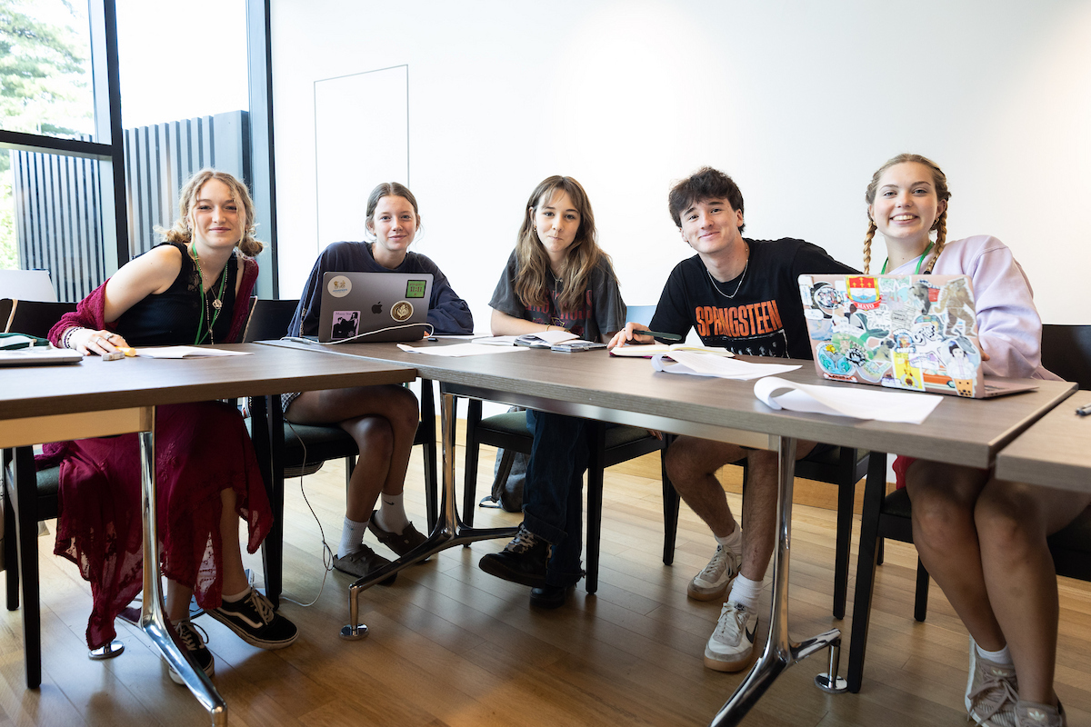 Group of students sitting at a table with laptops