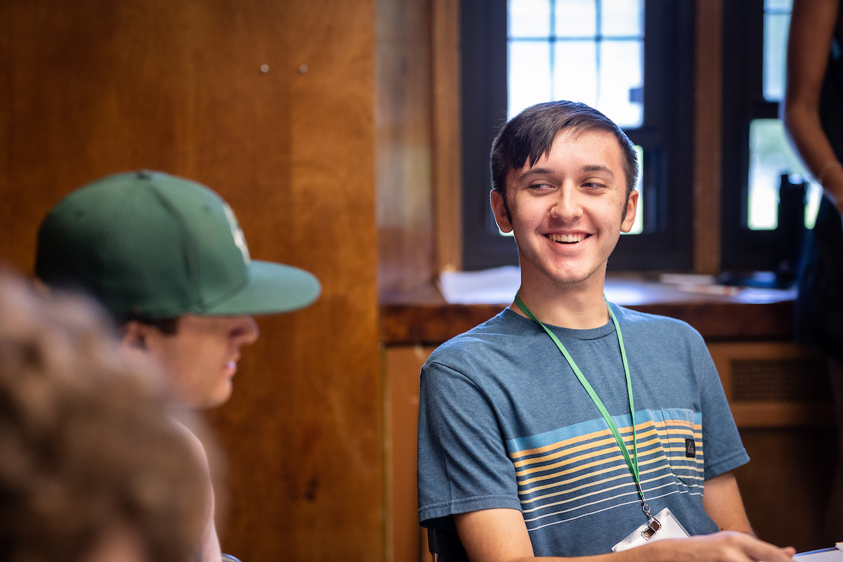 Student smiling at another at a round classroom table