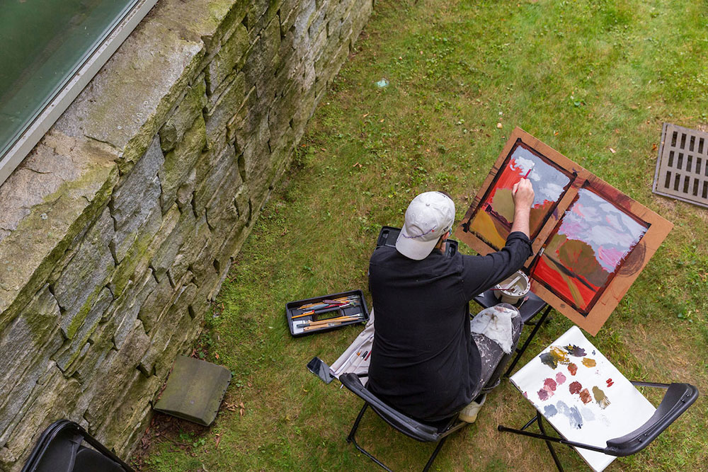 Overhead photo of a person sitting on a chair painting on an easel