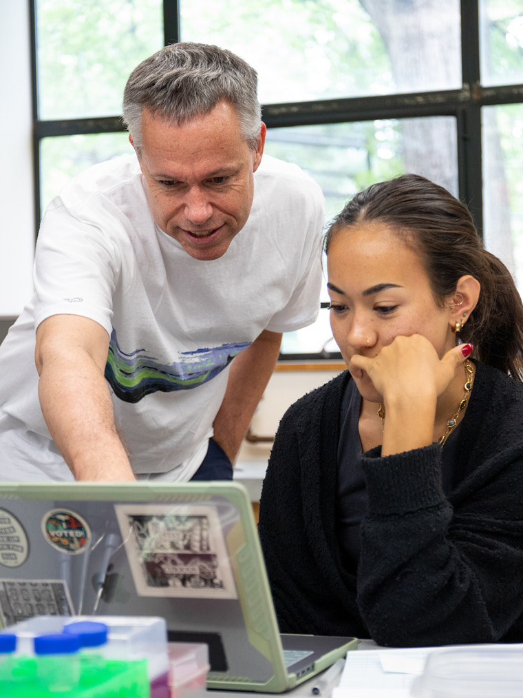 Drew Cressman and a student look at a laptop together