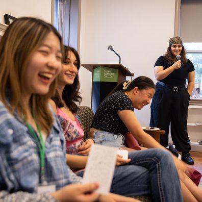 students laughing together seated near stage of auditorium